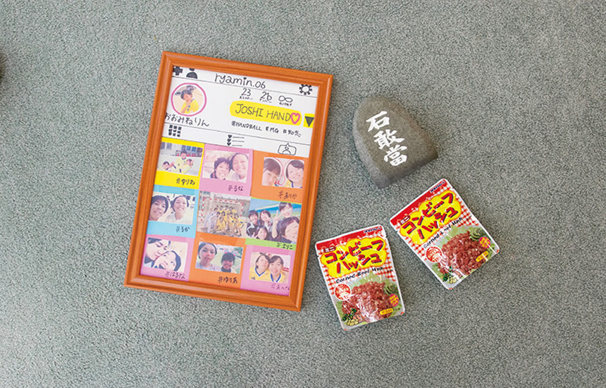 上京する大嶺さんにお姉さんがくれた石敢當。魔除けの意味を込めて玄関に置いている。 高校時代、女子ハンドボール部のマネージャーだった大嶺さんが選手達から貰ったメッセージボード。自宅の棚に飾っている。上地さんも選手としてメッセージを寄せている。 イメージ